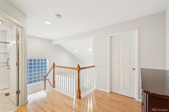 bonus room featuring light wood-type flooring, lofted ceiling, and baseboards