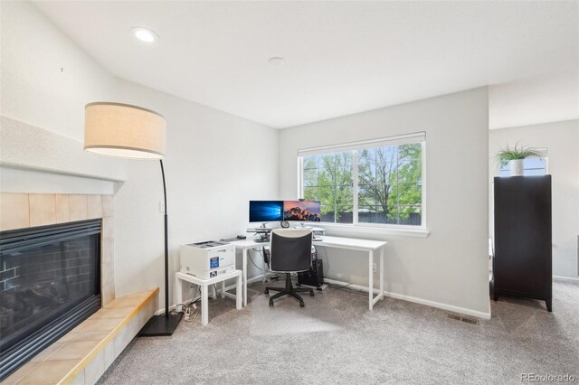 office space with a tiled fireplace, carpet, and baseboards