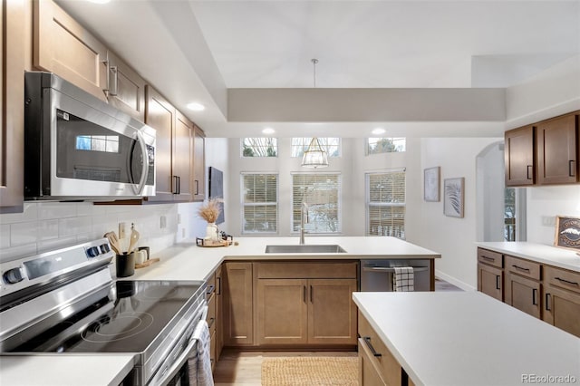 kitchen with stainless steel appliances, sink, kitchen peninsula, and decorative backsplash