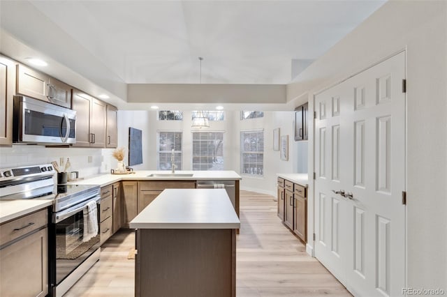 kitchen featuring sink, light hardwood / wood-style flooring, kitchen peninsula, a kitchen island, and stainless steel appliances