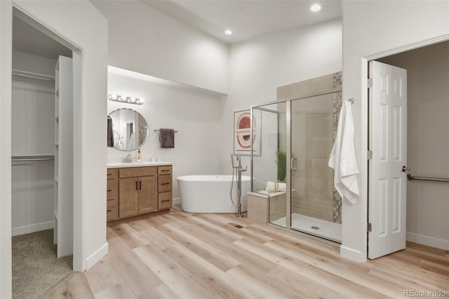 bathroom featuring wood-type flooring, separate shower and tub, and vanity