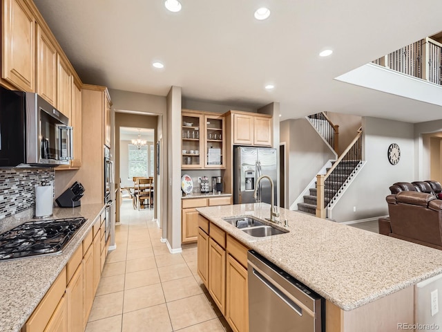 8522 S Dudley St, Littleton, CO 80128 - kitchen featuring stainless steel appliances, light brown cabinetry, open floor plan, light tile patterned floors, and tasteful backsplash