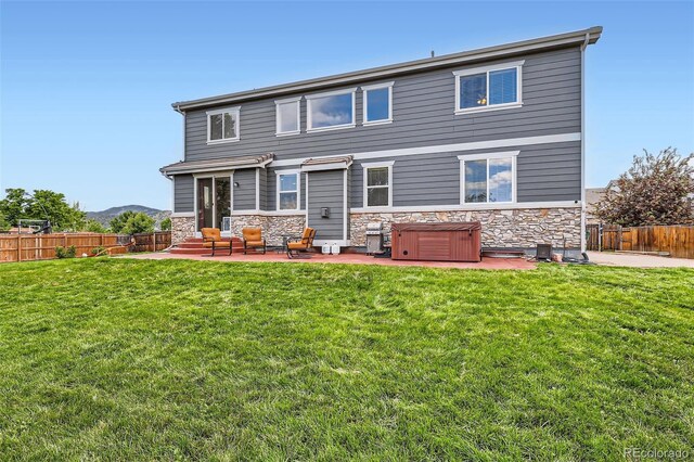 8522 S Dudley St, Littleton, CO 80128 - rear view of house with a patio, a hot tub, stone siding, and a fenced backyard