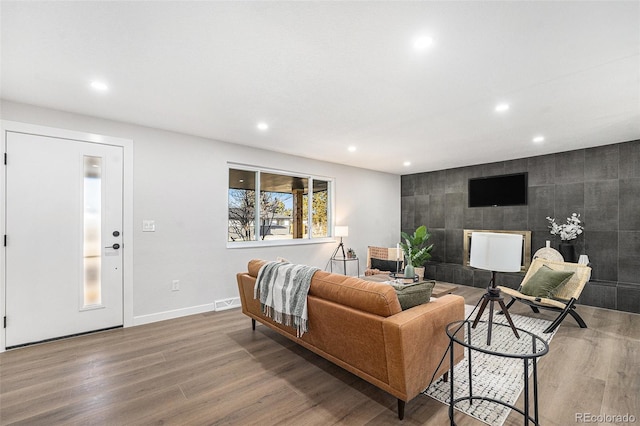 living area featuring recessed lighting, an accent wall, wood finished floors, visible vents, and baseboards