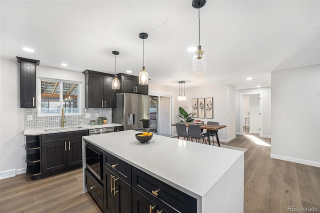 kitchen with wood finished floors, a sink, light countertops, backsplash, and stainless steel fridge with ice dispenser