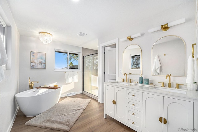 full bathroom with a stall shower, visible vents, a sink, and wood finished floors