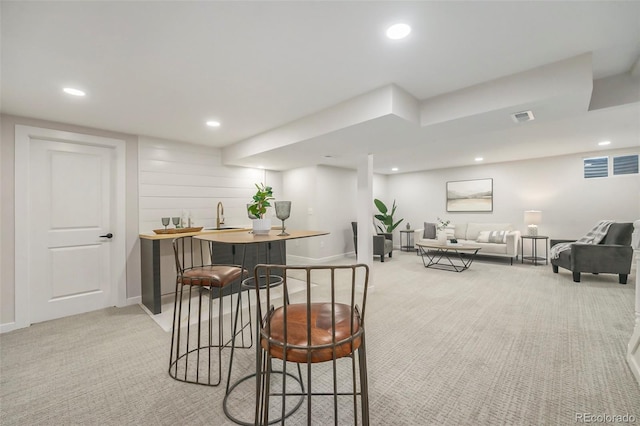 dining space with light carpet, recessed lighting, and wet bar