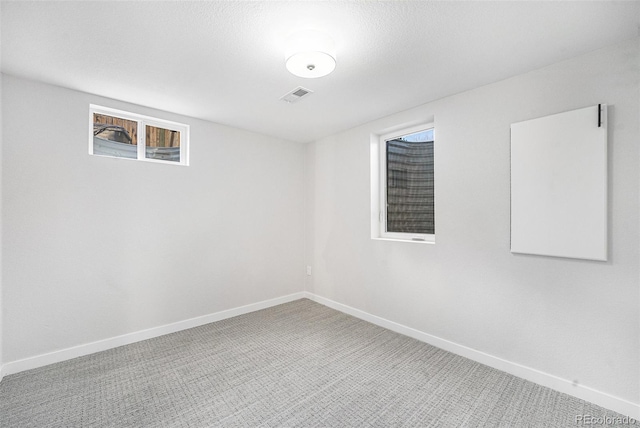 unfurnished room with visible vents, light carpet, and baseboards