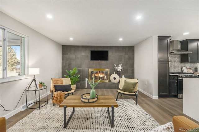 living area featuring a fireplace, recessed lighting, an accent wall, wood finished floors, and baseboards