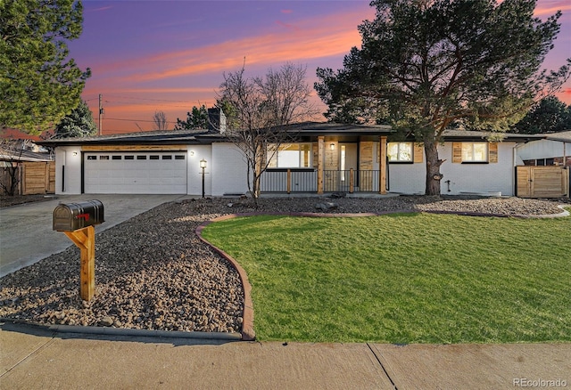 view of front facade with driveway, an attached garage, covered porch, a yard, and brick siding