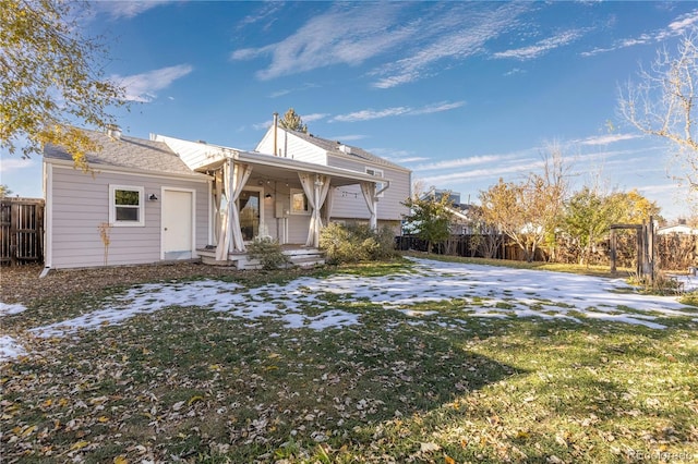 rear view of house featuring a lawn and covered porch