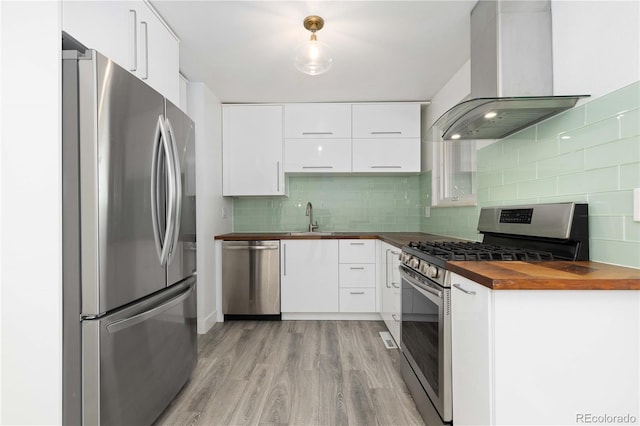 kitchen with white cabinets, wall chimney exhaust hood, stainless steel appliances, and wooden counters