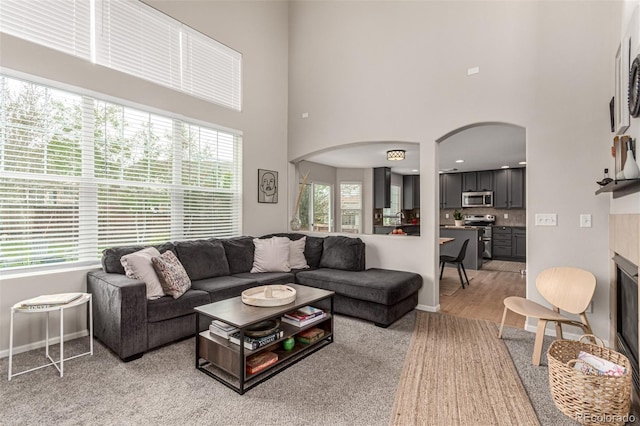 4873 S Fultondale Way, Aurora, CO 80016 - living area with arched walkways, a towering ceiling, baseboards, and light wood finished floors