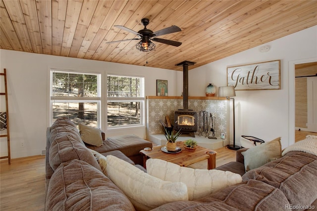 living room featuring wood ceiling, ceiling fan, light wood-type flooring, vaulted ceiling, and a wood stove