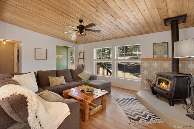 living room with light wood-type flooring, a wood stove, ceiling fan, wooden ceiling, and vaulted ceiling