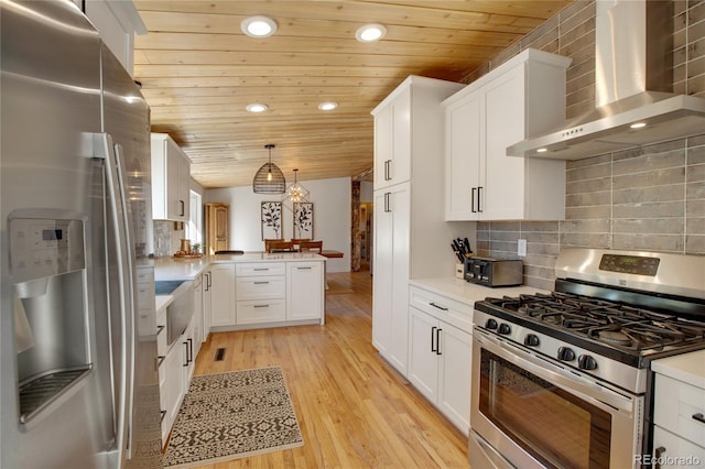 kitchen featuring white cabinetry, light hardwood / wood-style floors, stainless steel appliances, wall chimney exhaust hood, and pendant lighting