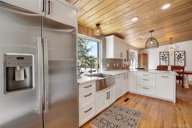 kitchen featuring kitchen peninsula, white cabinetry, light hardwood / wood-style floors, pendant lighting, and stainless steel refrigerator with ice dispenser