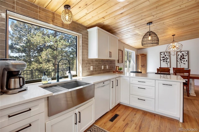 kitchen featuring kitchen peninsula, a healthy amount of sunlight, hanging light fixtures, white dishwasher, and light hardwood / wood-style floors