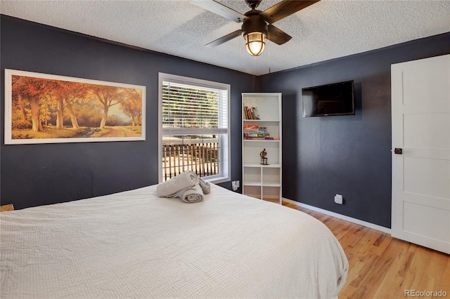 bedroom with a textured ceiling, light wood-type flooring, and ceiling fan