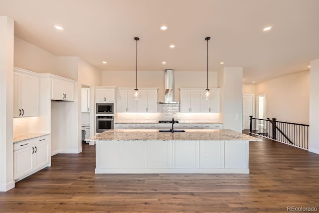 kitchen featuring stainless steel appliances, a sink, white cabinets, backsplash, and wall chimney exhaust hood