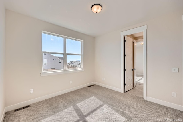 empty room featuring baseboards, visible vents, and light colored carpet