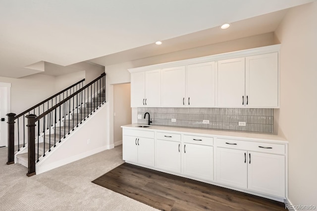 kitchen with light countertops, tasteful backsplash, a sink, and white cabinets