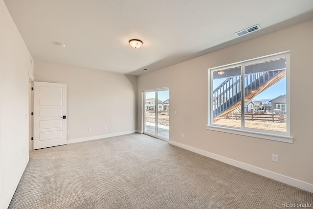 spare room with baseboards, visible vents, and light colored carpet