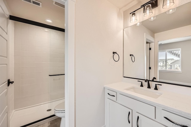 bathroom with toilet, a stall shower, vanity, and visible vents