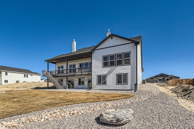 rear view of property with board and batten siding, stairs, and a lawn