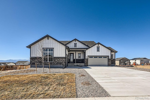 view of front of house featuring driveway, a shingled roof, board and batten siding, and stone siding