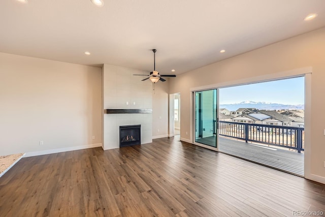 unfurnished living room featuring recessed lighting, baseboards, a tiled fireplace, and wood finished floors