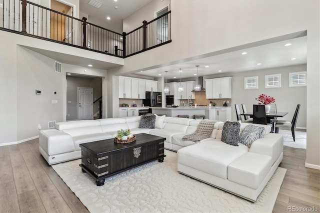 living room with a towering ceiling and light hardwood / wood-style floors