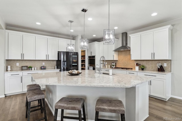 kitchen featuring wall chimney range hood, decorative light fixtures, stainless steel appliances, and tasteful backsplash