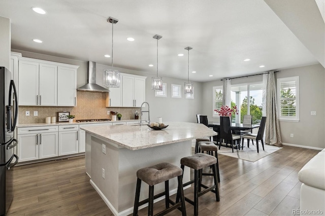 kitchen with decorative light fixtures, wall chimney range hood, backsplash, and dark wood-type flooring