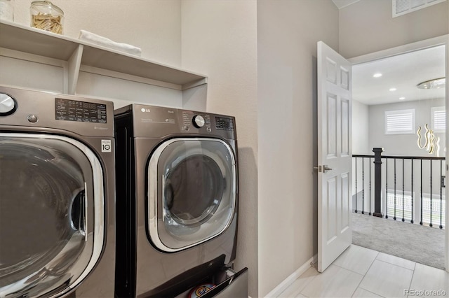 laundry area with washer and clothes dryer and light tile flooring