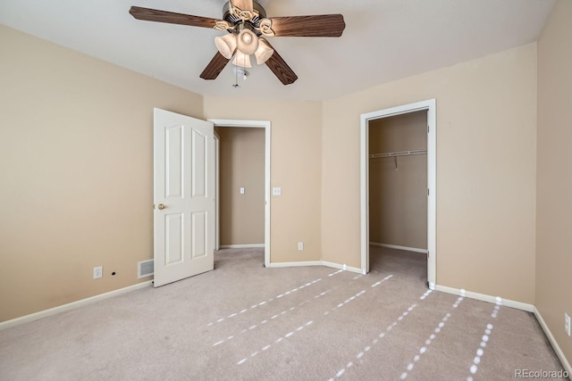 unfurnished bedroom featuring ceiling fan, a closet, light colored carpet, and a spacious closet