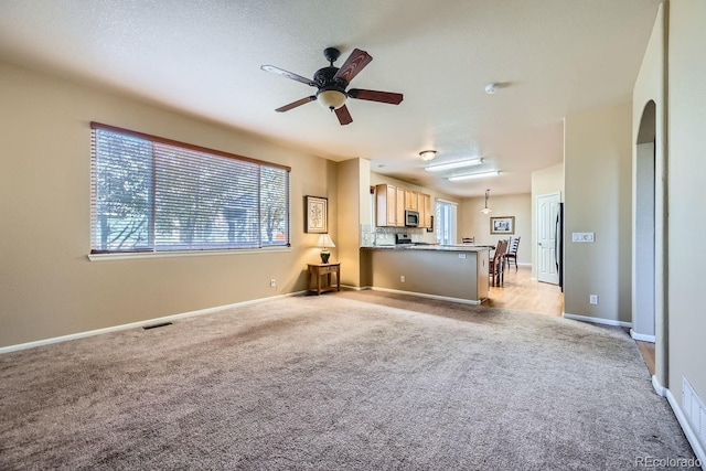 unfurnished living room with light carpet, ceiling fan, and a textured ceiling