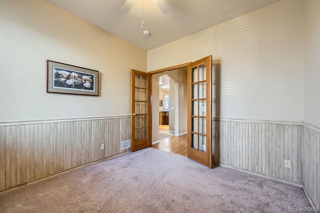 carpeted empty room featuring ceiling fan and french doors