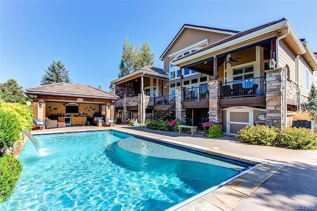 back of house with pool water feature, ceiling fan, a patio area, and a balcony