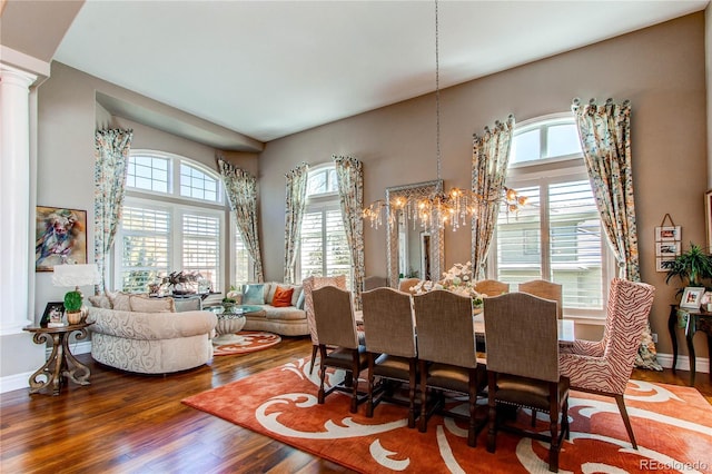 dining area featuring decorative columns, a wealth of natural light, an inviting chandelier, and hardwood / wood-style flooring