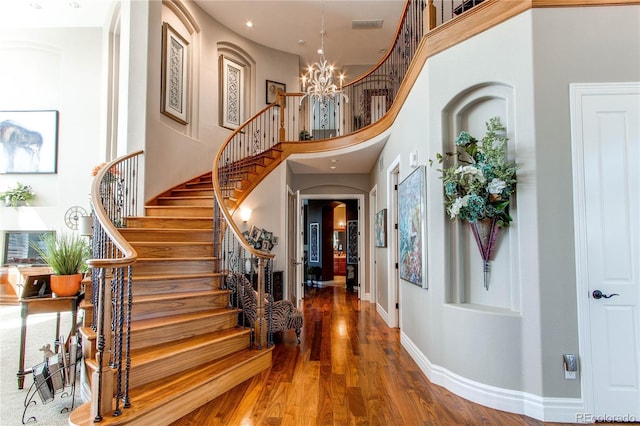 foyer entrance featuring hardwood / wood-style floors, a notable chandelier, and a high ceiling