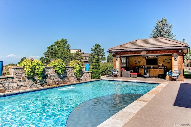 view of pool featuring pool water feature, an outbuilding, and a patio