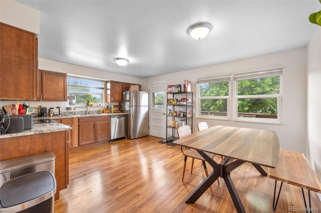 8485 W 44th Ave, Wheat Ridge, CO 80033 - kitchen featuring appliances with stainless steel finishes, brown cabinets, light wood-style floors, and light stone countertops