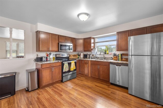 8485 W 44th Ave, Wheat Ridge, CO 80033 - kitchen featuring stainless steel appliances, light wood-style floors, brown cabinetry, and light stone counters
