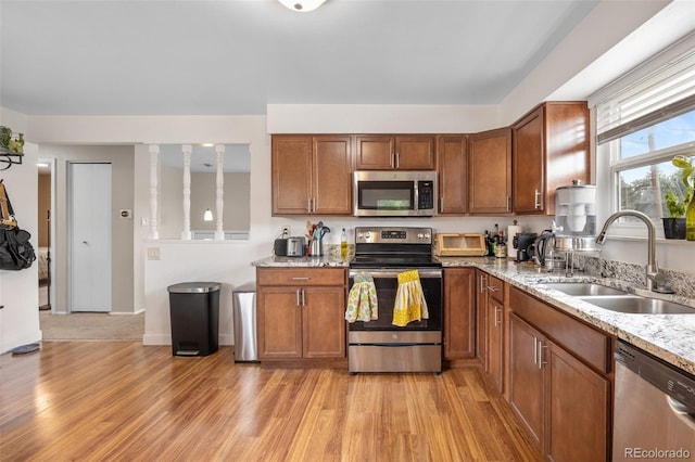 8485 W 44th Ave, Wheat Ridge, CO 80033 - kitchen featuring stainless steel appliances, light wood finished floors, brown cabinetry, and light stone counters