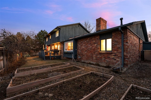 2090 S Gray Dr, Lakewood, CO 80227 - back of property at dusk featuring fence, a garden, a chimney, a deck, and brick siding