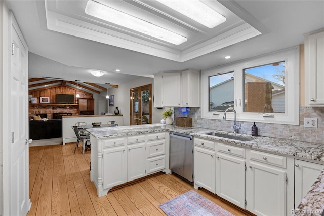 2090 S Gray Dr, Lakewood, CO 80227 - kitchen featuring a tray ceiling, light wood-style flooring, a peninsula, a sink, and stainless steel dishwasher