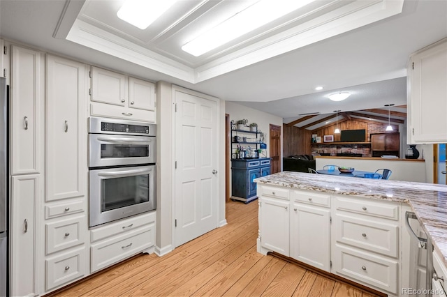 2090 S Gray Dr, Lakewood, CO 80227 - kitchen with light wood finished floors, stainless steel double oven, a peninsula, vaulted ceiling, and white cabinets