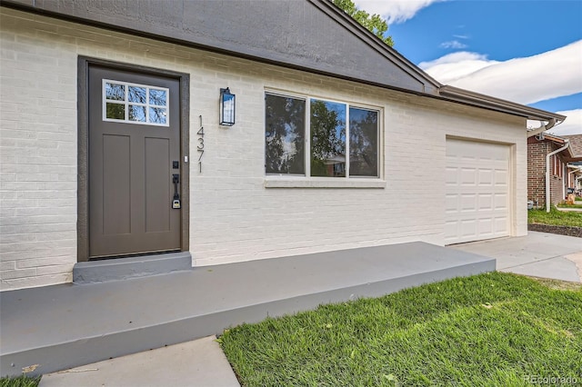 14317 Olmsted Dr, Denver, CO 80239 - view of exterior entry featuring driveway, brick siding, and a garage