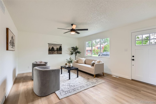 14317 Olmsted Dr, Denver, CO 80239 - living room with light wood-type flooring, a ceiling fan, plenty of natural light, baseboards, and a textured ceiling